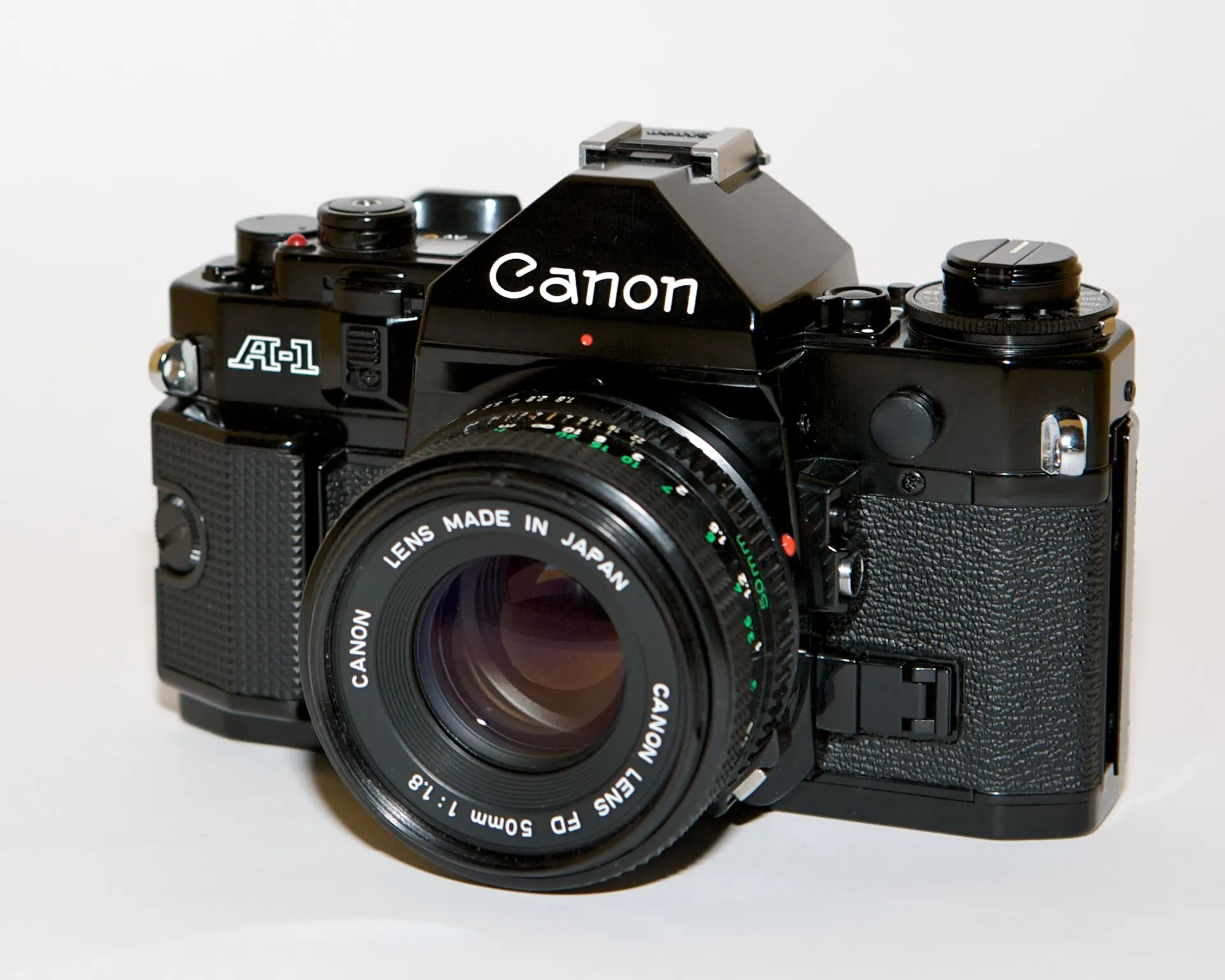 Black Canon A-1 35mm SLR with a Canon FD 50mm f/1.8 lens, front three-quarter view on a white background
