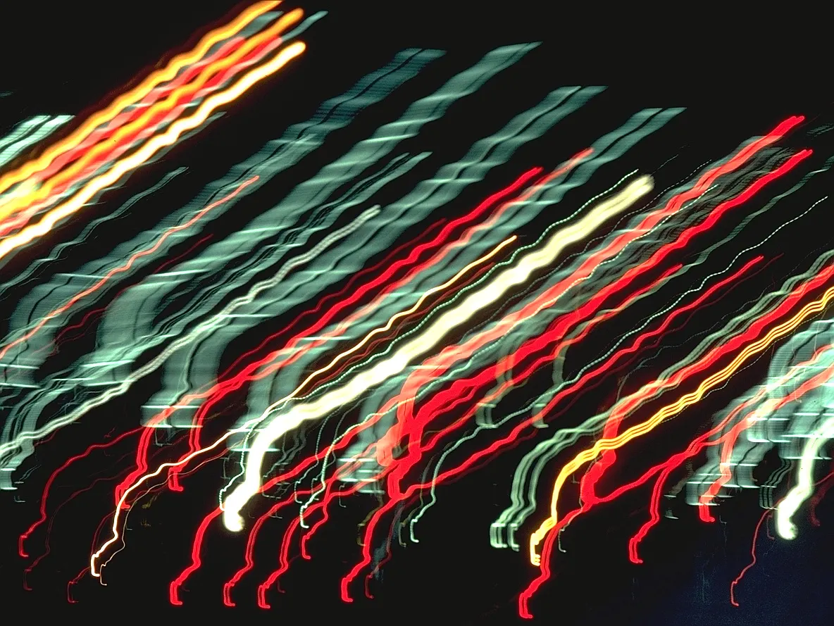 Streaks of red, white and green light running diagonally across a dark frame