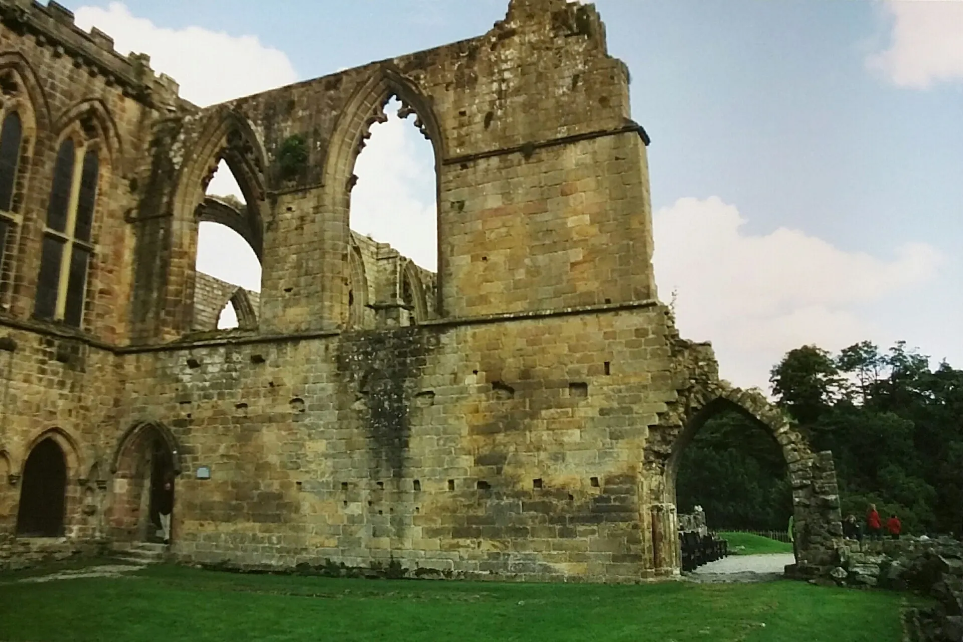 Stone ruins of a Gothic abbey with empty arched windows on a green lawn