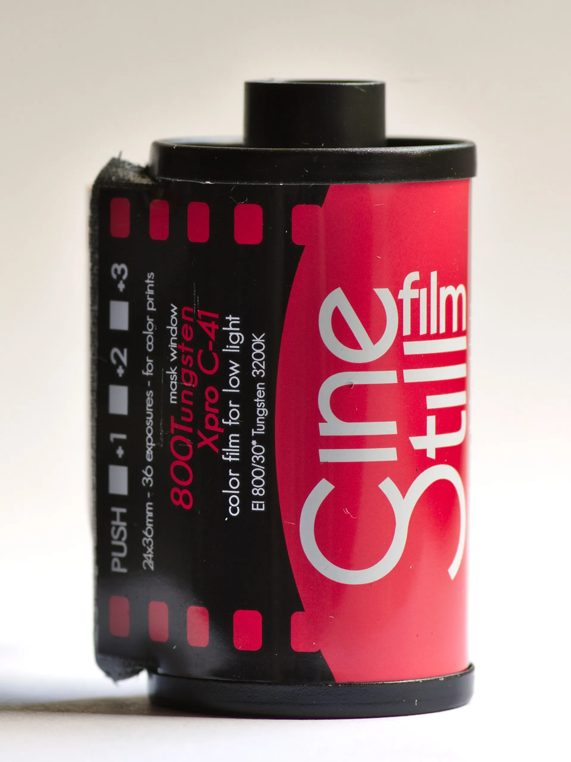 A CineStill 800Tungsten 35mm film cassette with its red and black label, standing on a plain white background