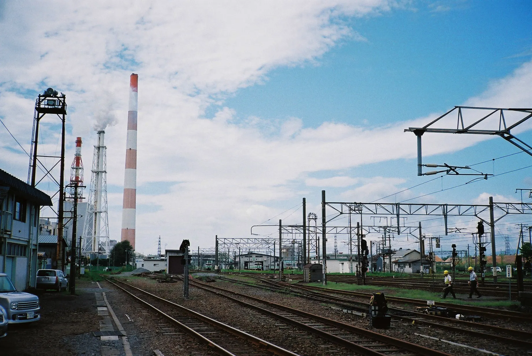 Train platform at Tomakomai Station looking toward the tall chimney of the Oji Paper mill