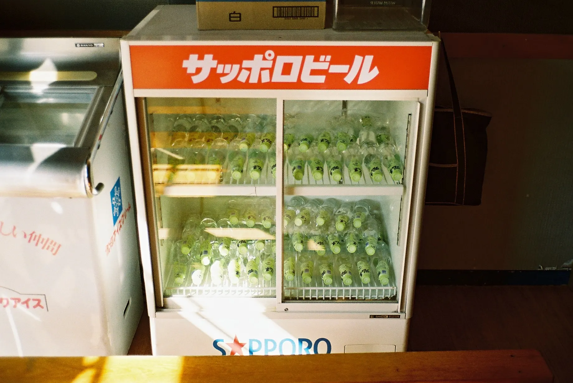 A vintage Sapporo Beer drinks cooler filled with soda bottles