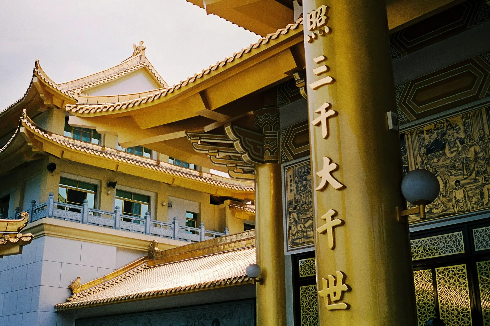 Gold-trimmed roofs and pillars of a Buddhist temple in bright sun