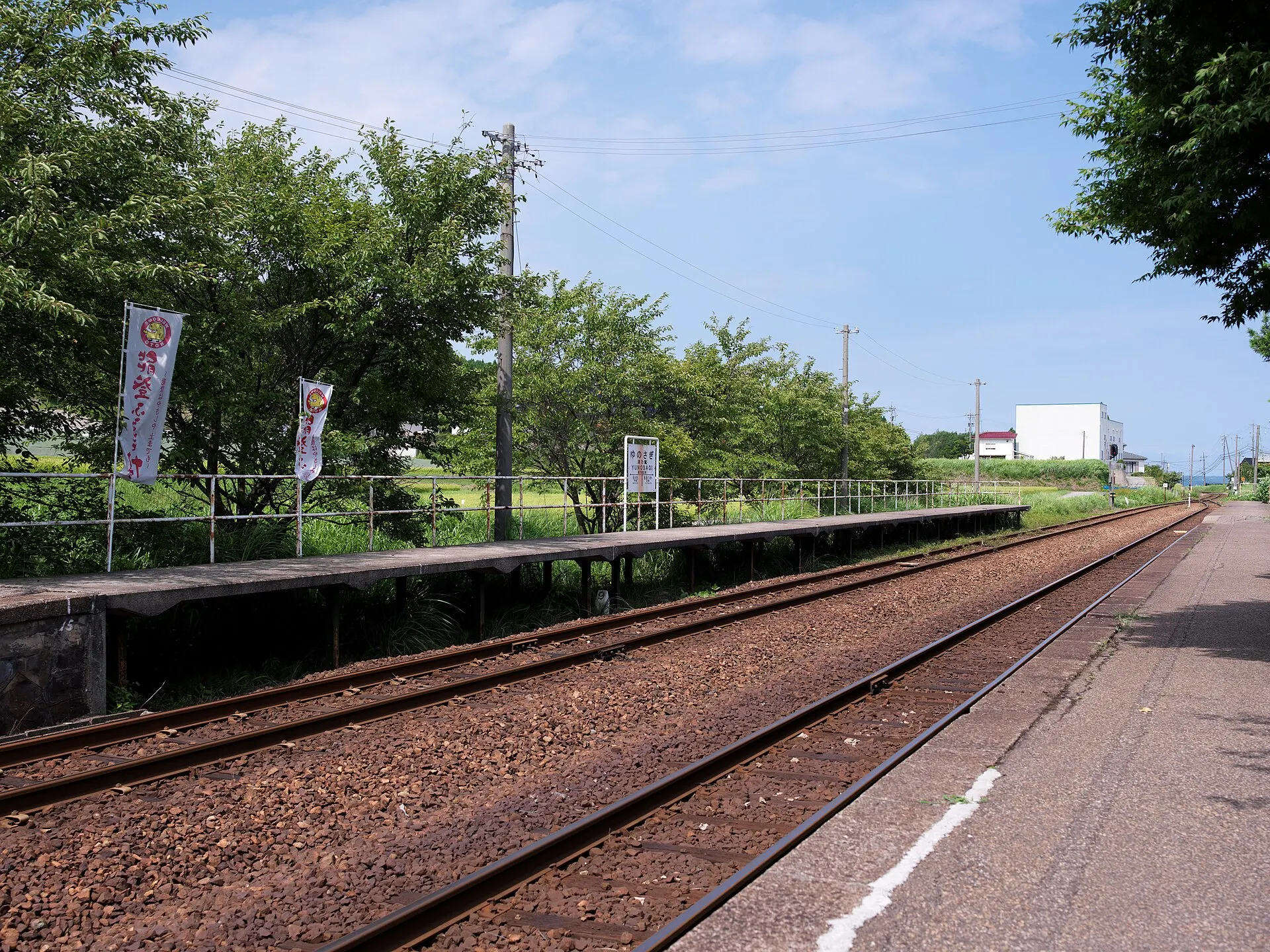 Empty rural railway platform and tracks under a summer sky