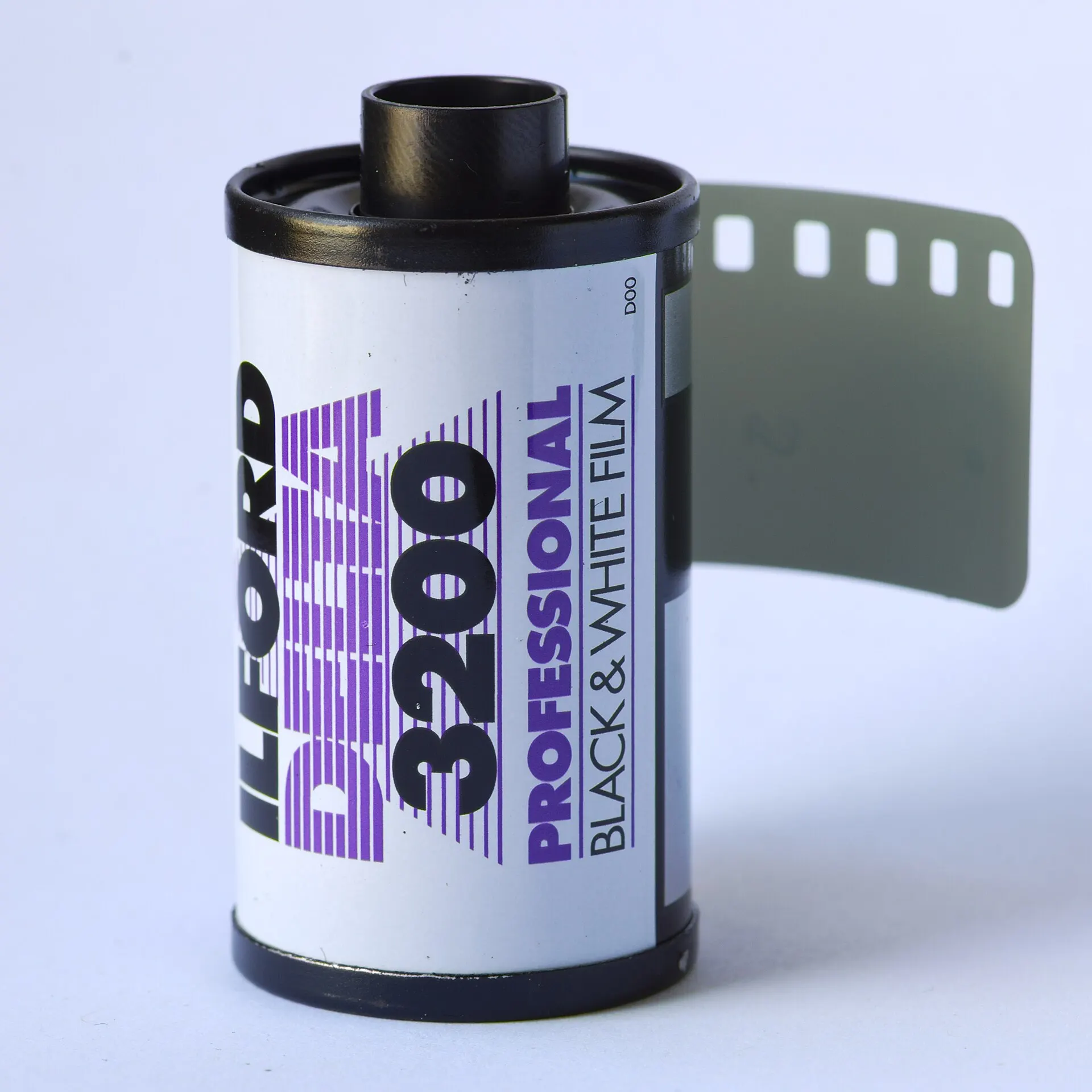 A 36-exposure 35mm cassette of Ilford Delta 3200 Professional black and white film with the leader pulled out, on a plain white background