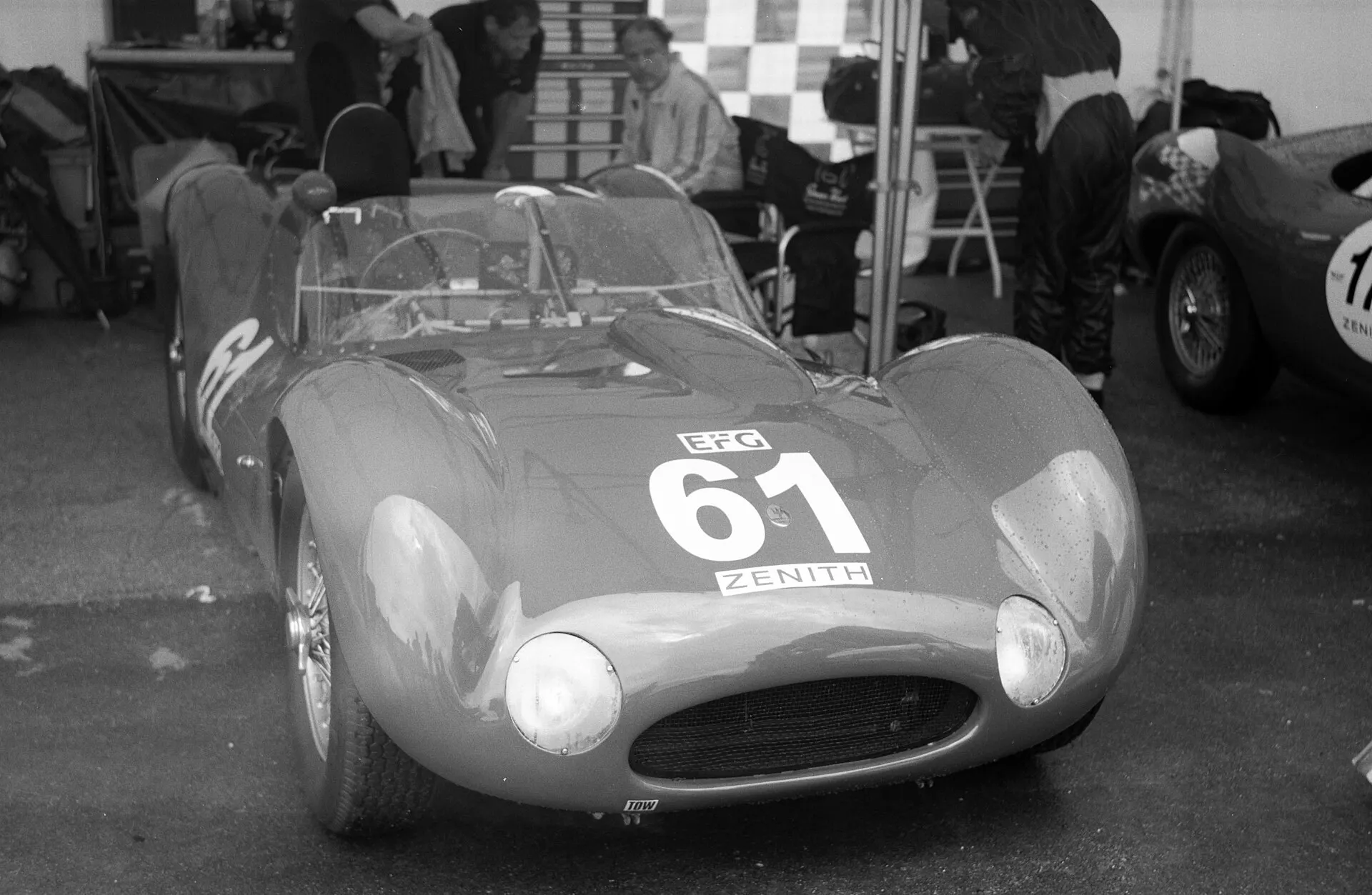 A 1960 Maserati Tipo 61 Birdcage race car with number 61 parked in a paddock