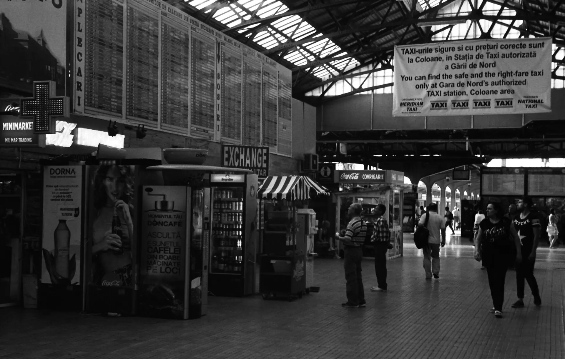 The concourse of a large train station with departure boards and travelers