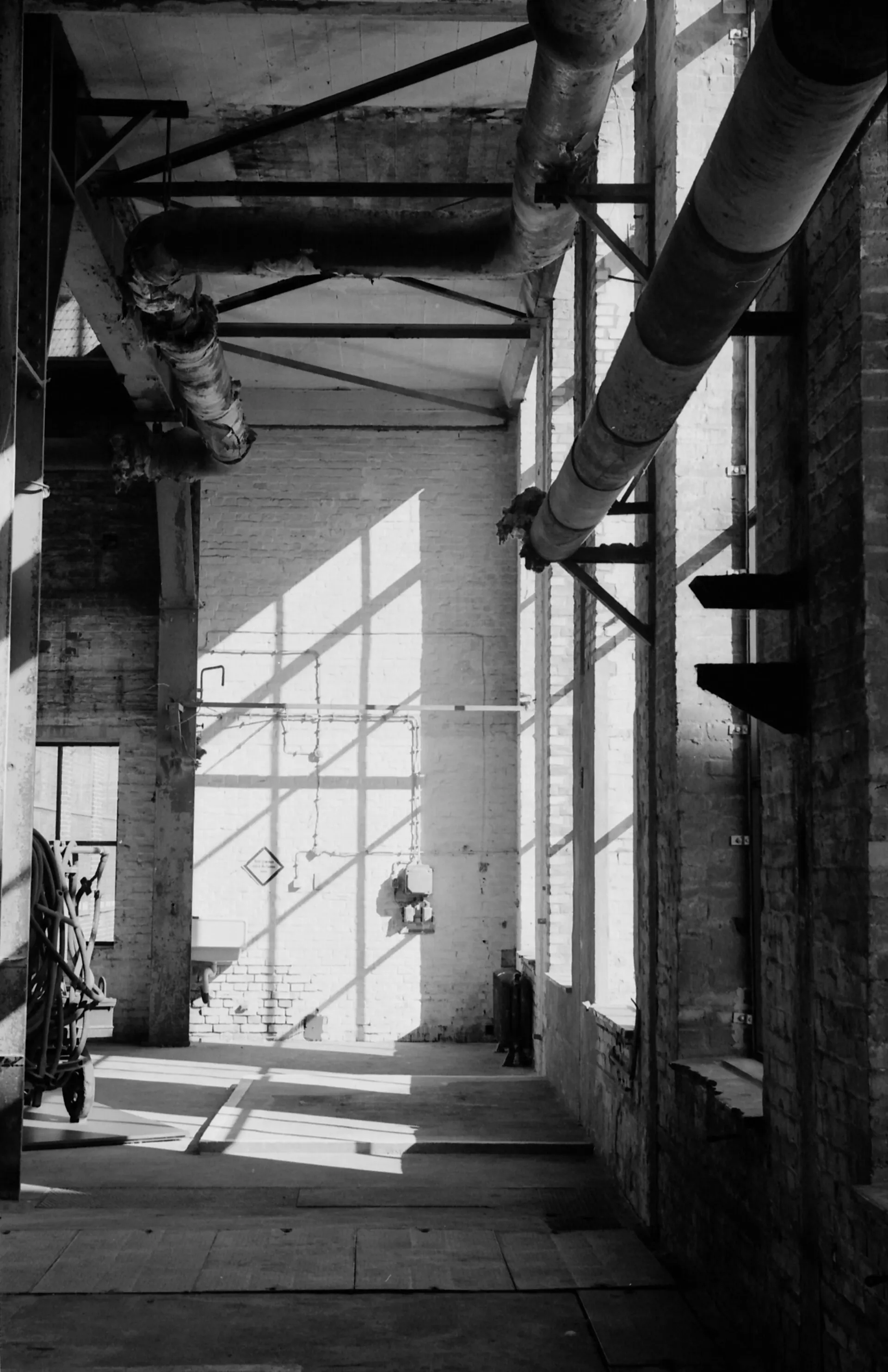 Sunlight falling through tall windows inside an old power plant hall