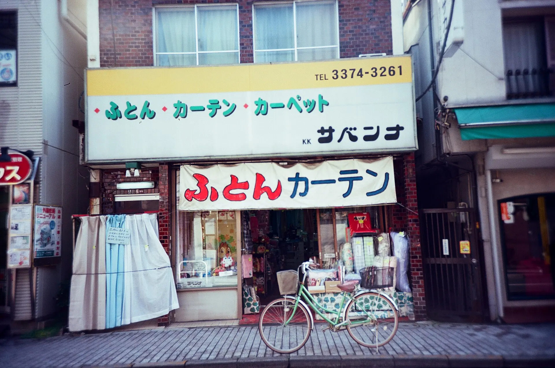 A small bedding and curtain shop in a Tokyo residential street, with a bicycle parked in front