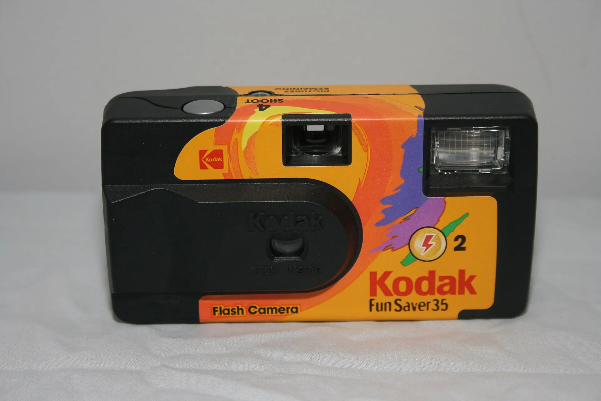 An older Kodak FunSaver 35 single-use flash camera with an orange and purple wrap, front view on a white background