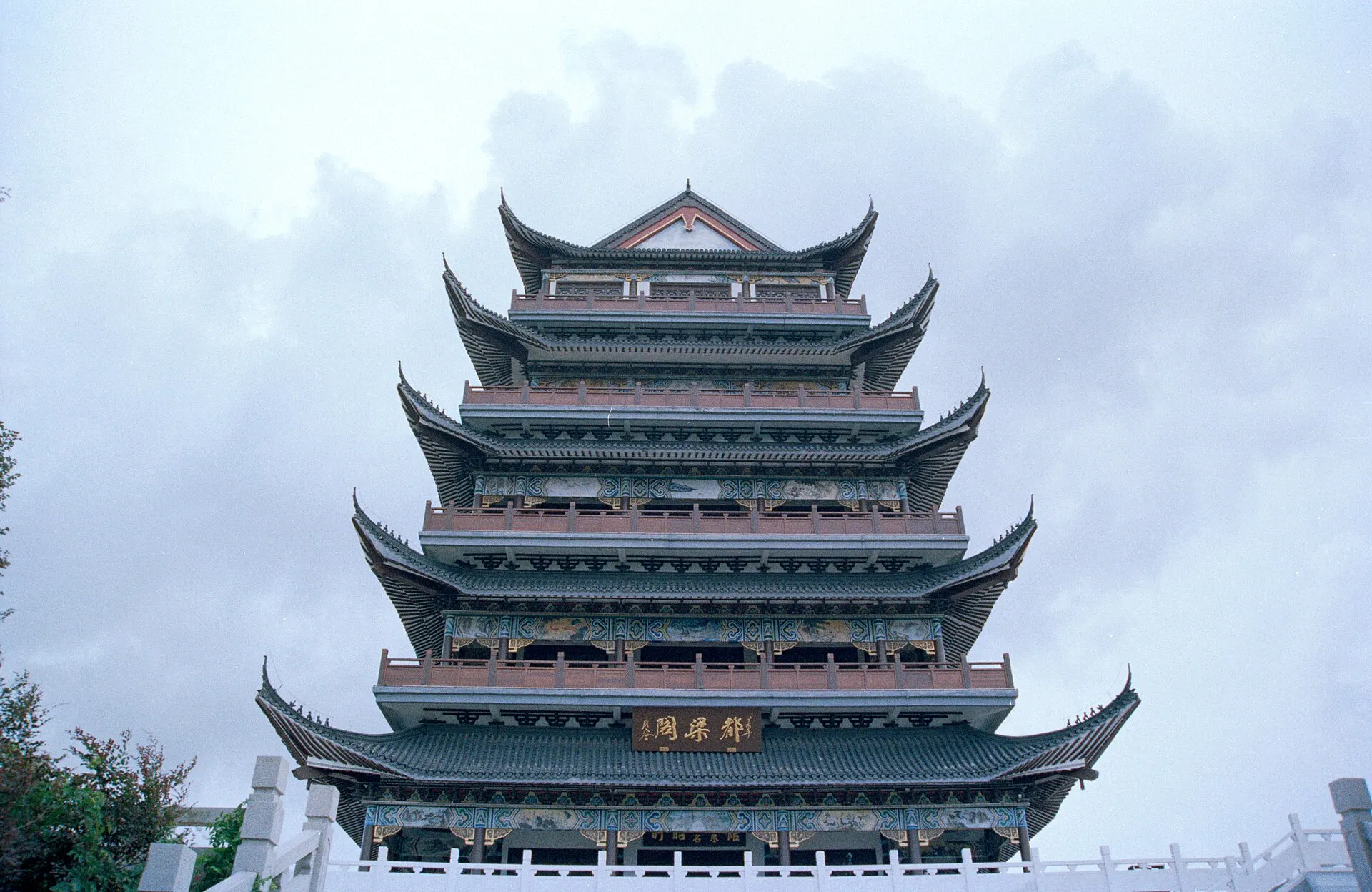 Low-angle view of a tiered Chinese pavilion against a pale cloudy sky