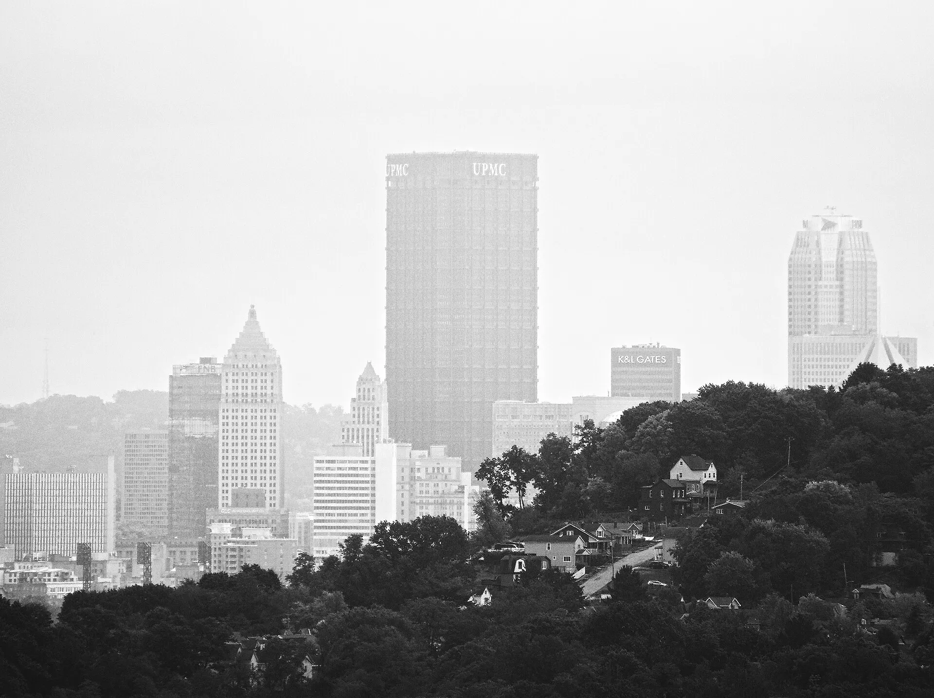 Pittsburgh downtown skyline in haze behind a wooded hill