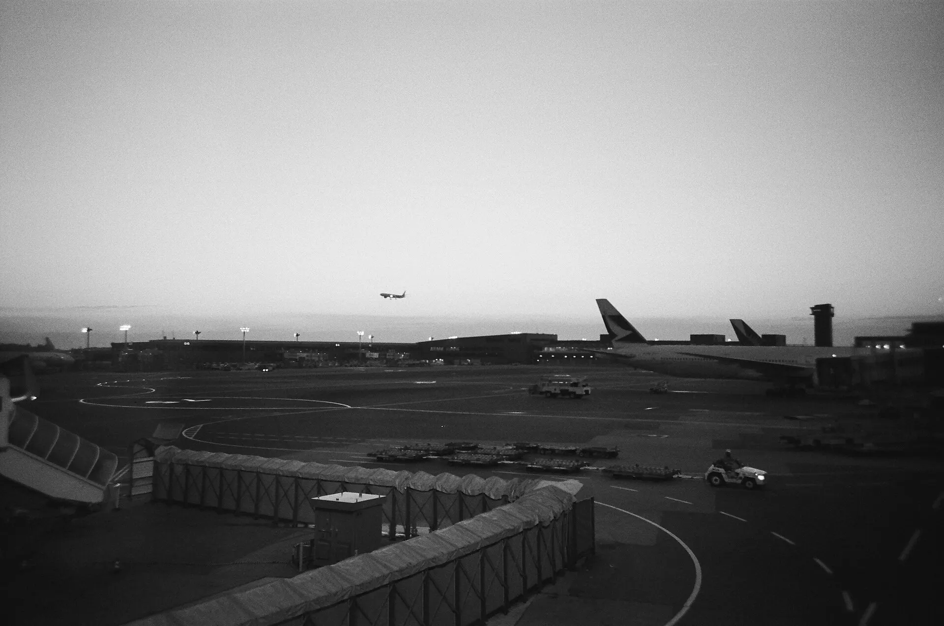 Airport apron with parked jets and a plane taking off in the distance