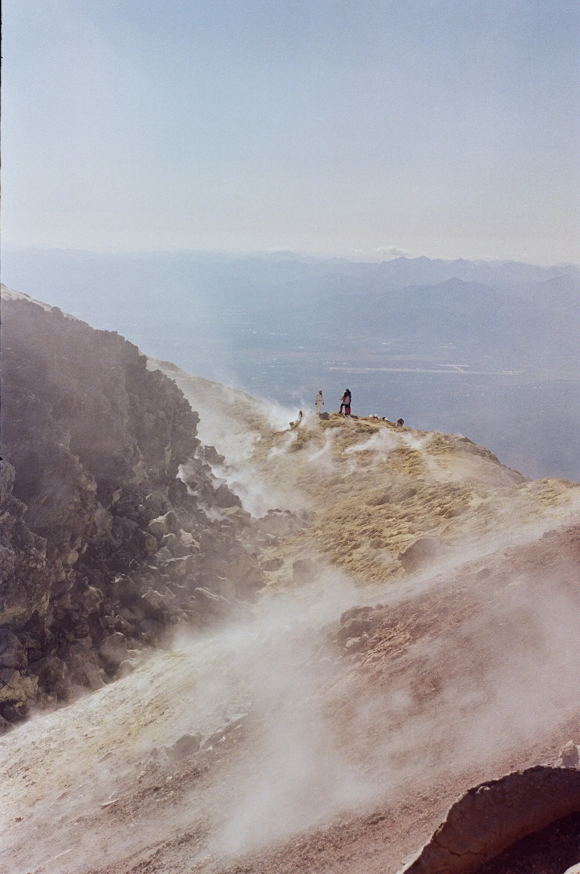 Steam rising from a rocky hillside under a pale sky