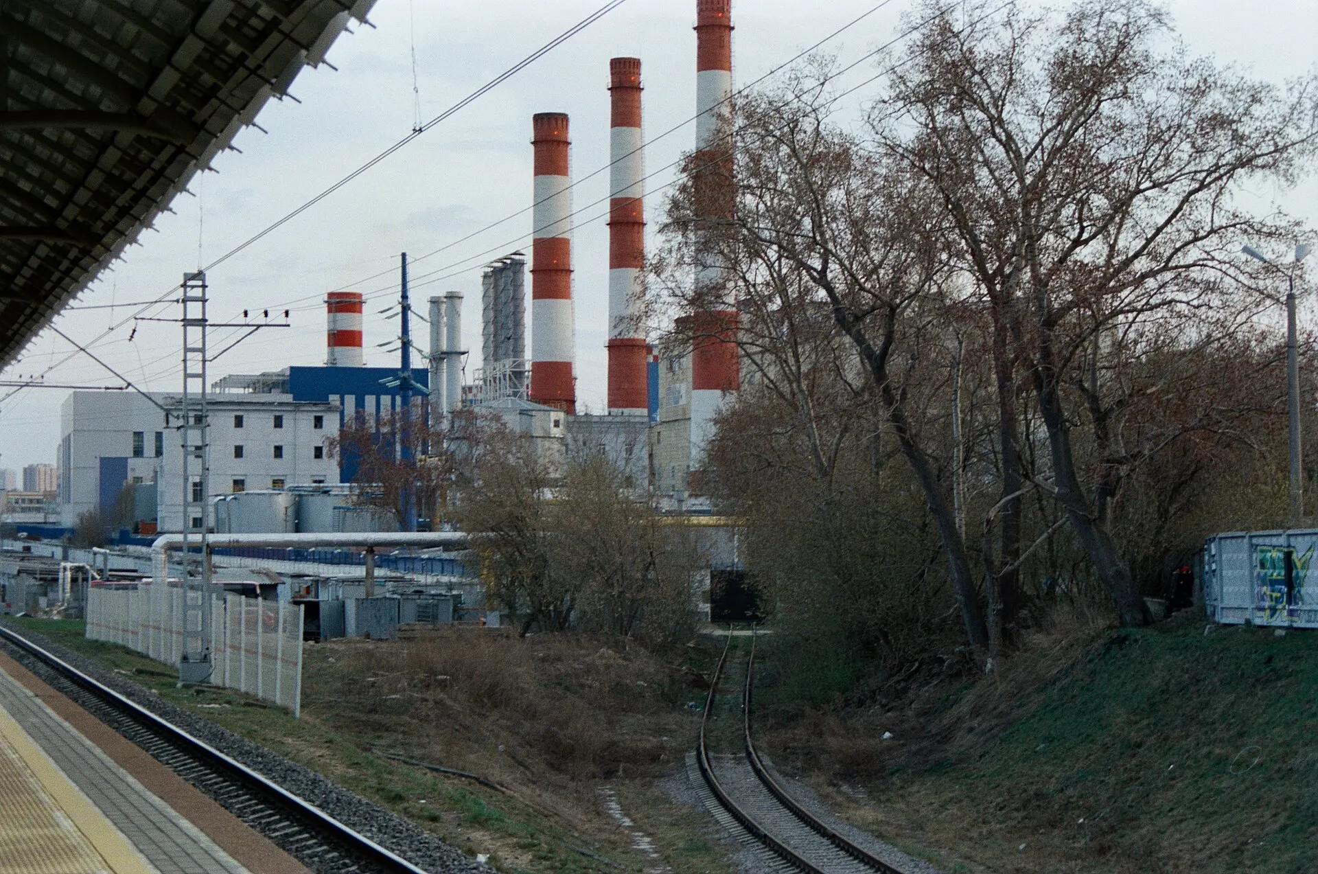 Red and white power plant chimneys beside a railway branch line and bare spring trees