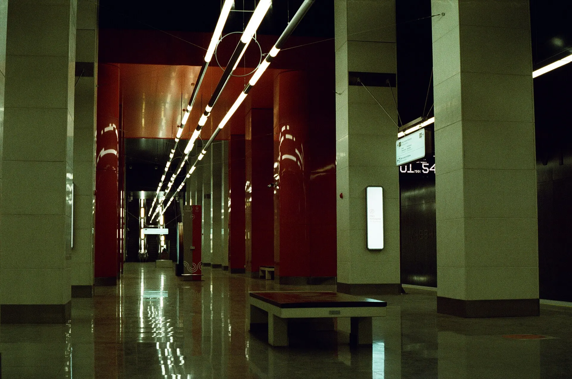 Empty metro platform with red walls, pale columns and strip lights