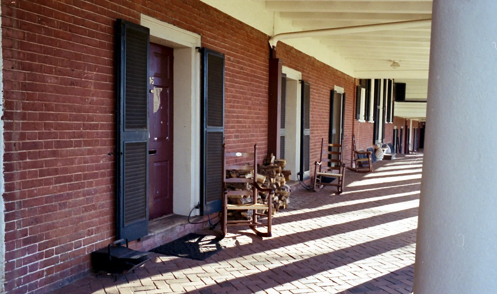 Brick colonnade with dark shutters and long morning shadows