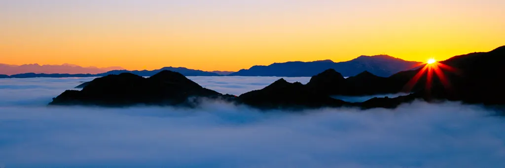 Sunrise over a sea of clouds with dark mountain ridges, seen from above Malibu