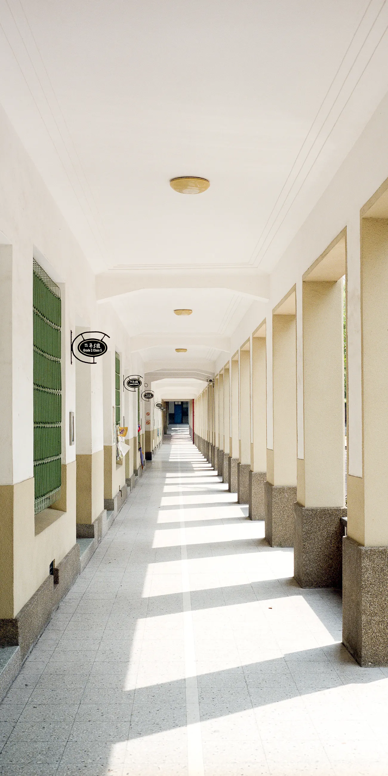 Long empty school corridor with white columns and sunlight falling across the floor