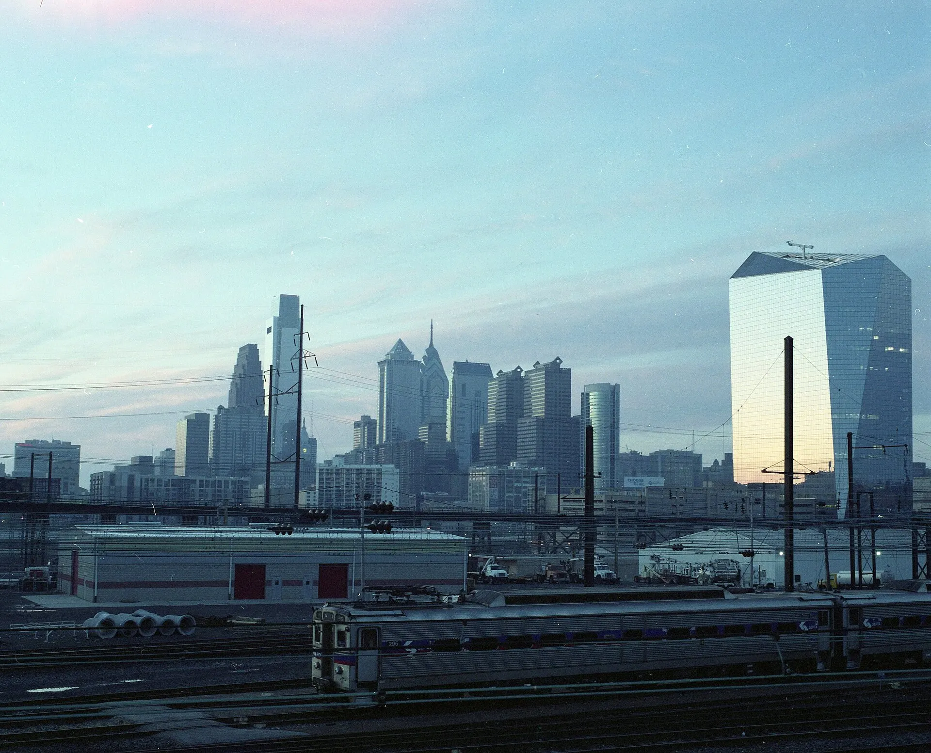 Center City Philadelphia skyline at dawn above rail yards, in soft blue light