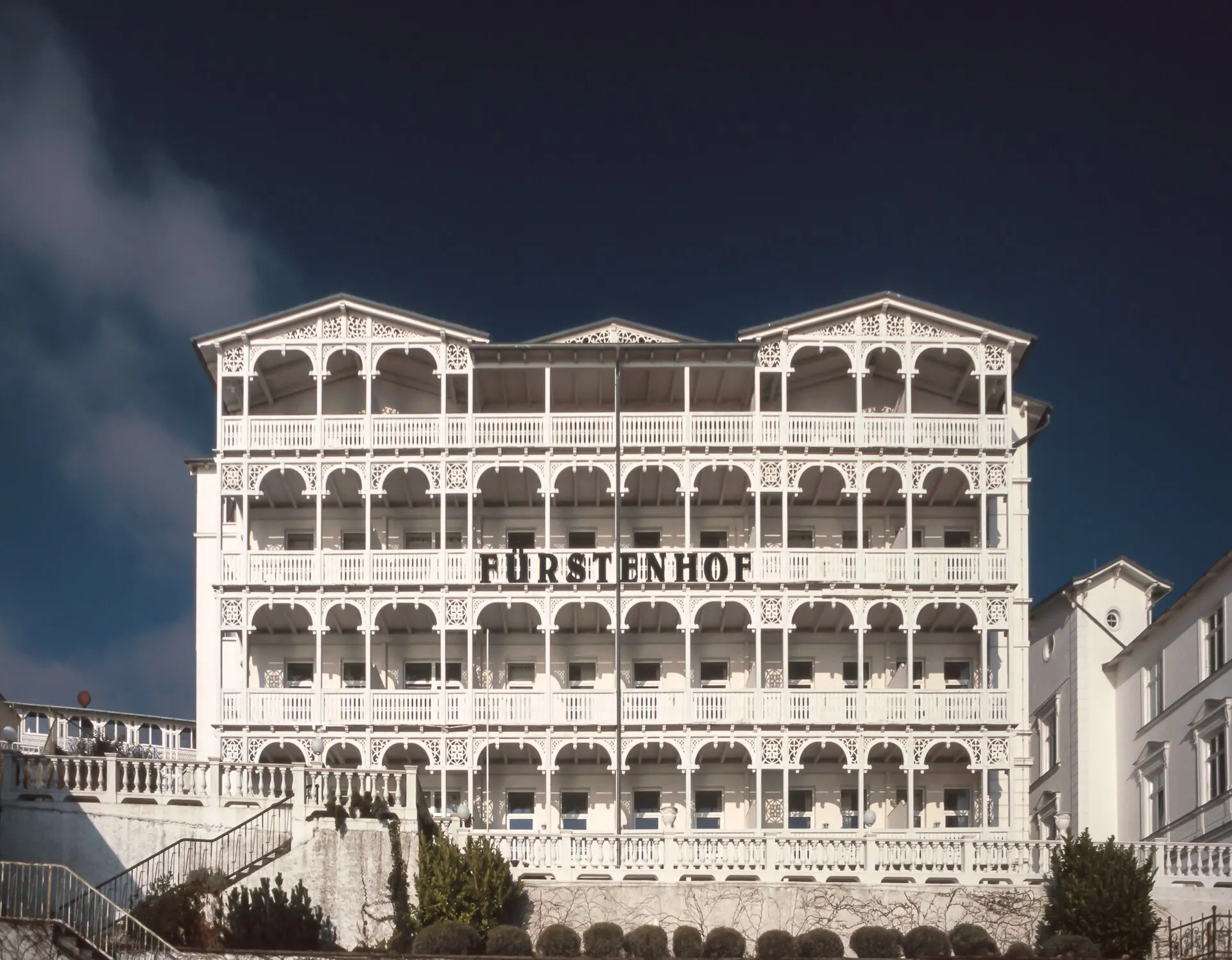 The white Hotel Fuerstenhof with rows of balconies under a dark sky