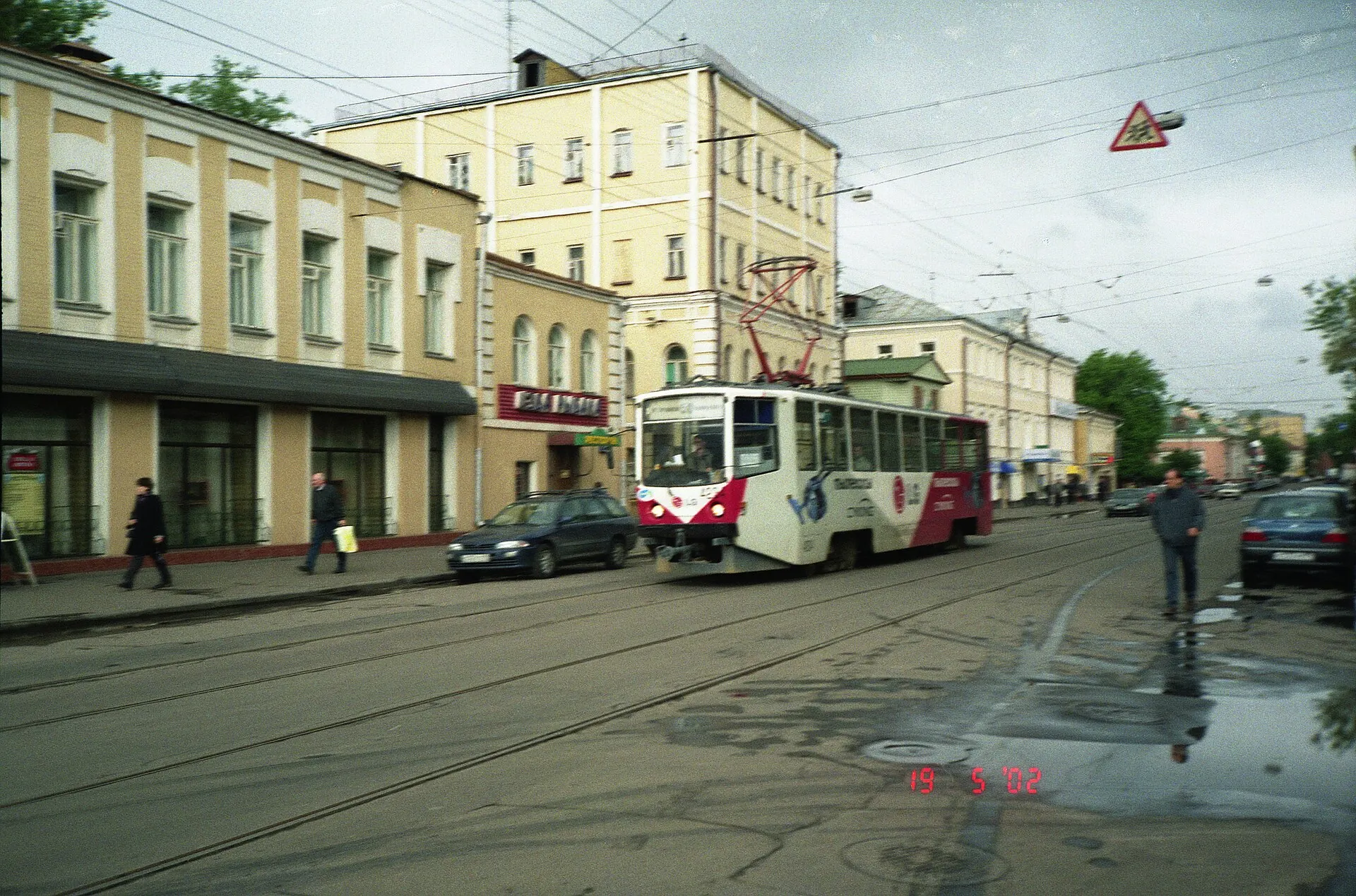 Red and white tram on a wet Moscow street lined with old buildings