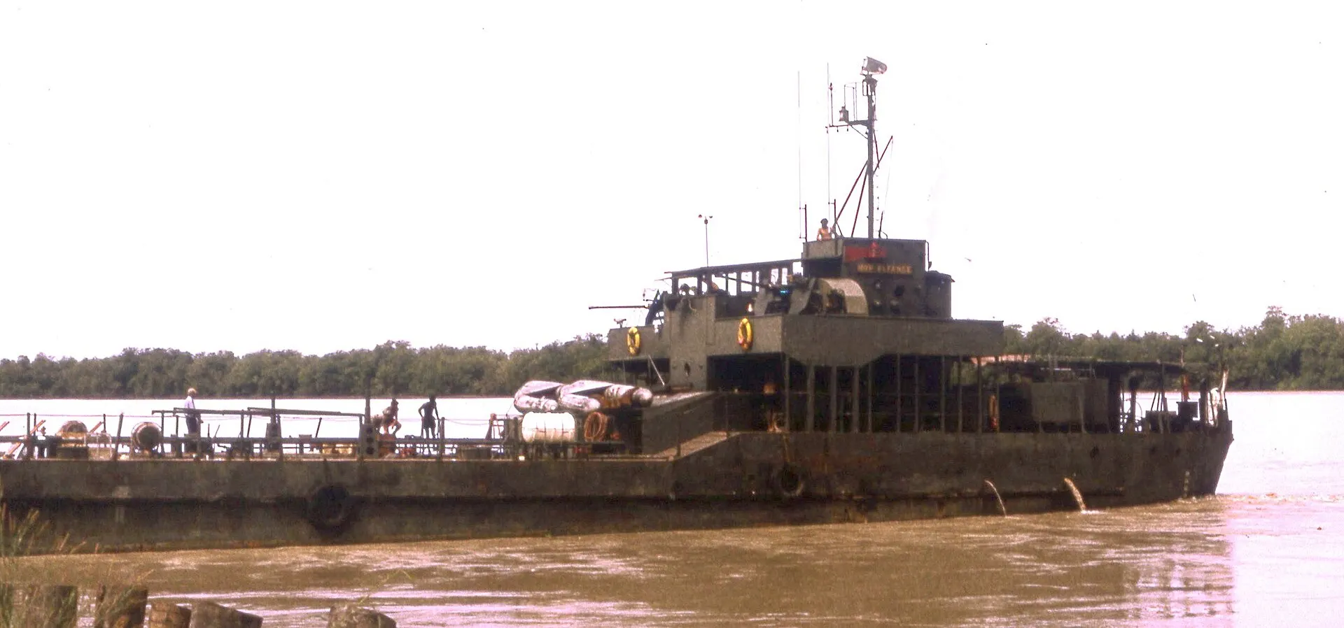 Portuguese landing craft Alfange moored on a brown river with trees along the far bank