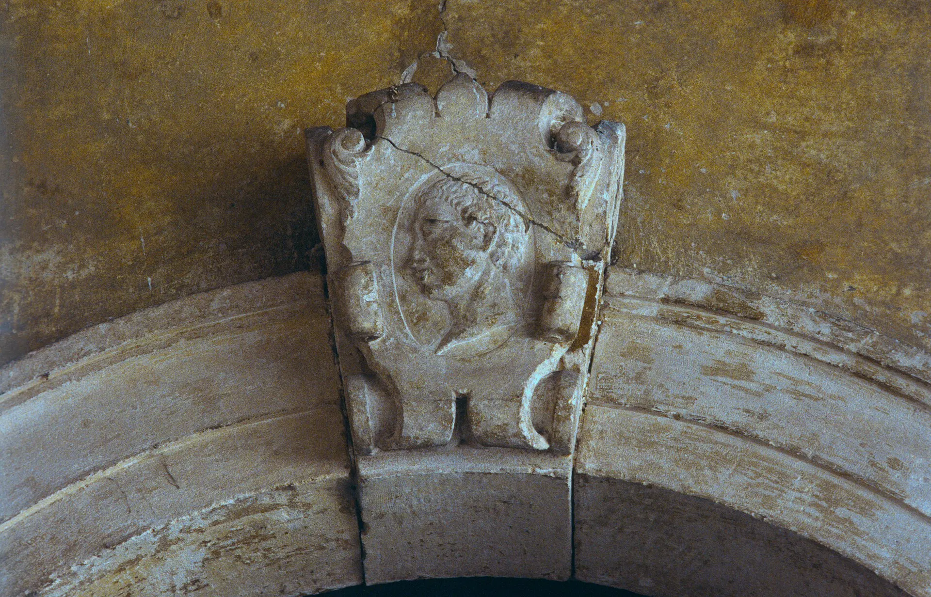 Close view of a carved stone keystone with a male profile above an arched doorway