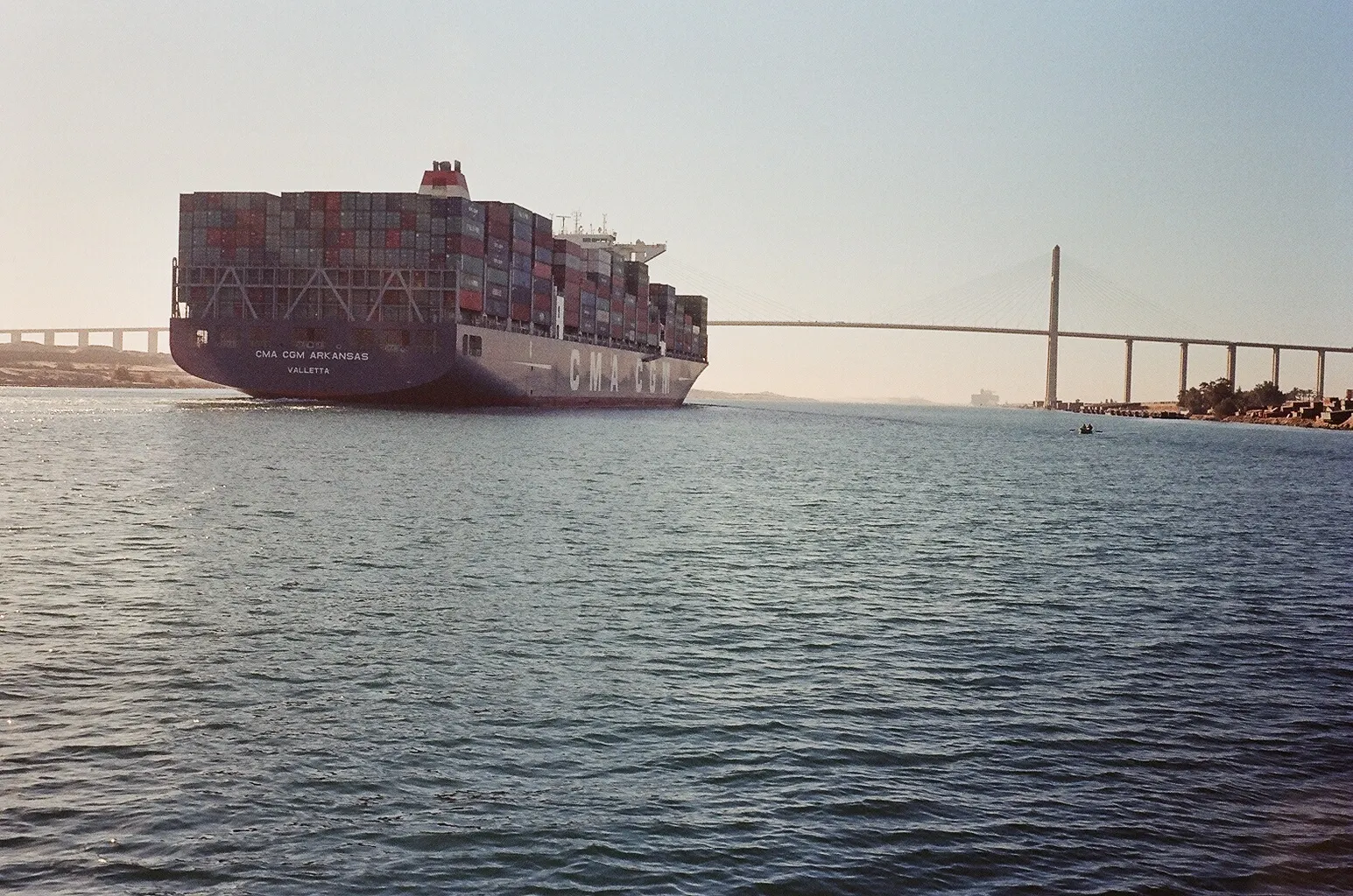 Container ship CMA CGM Arkansas passing through the Suez Canal with a bridge behind it