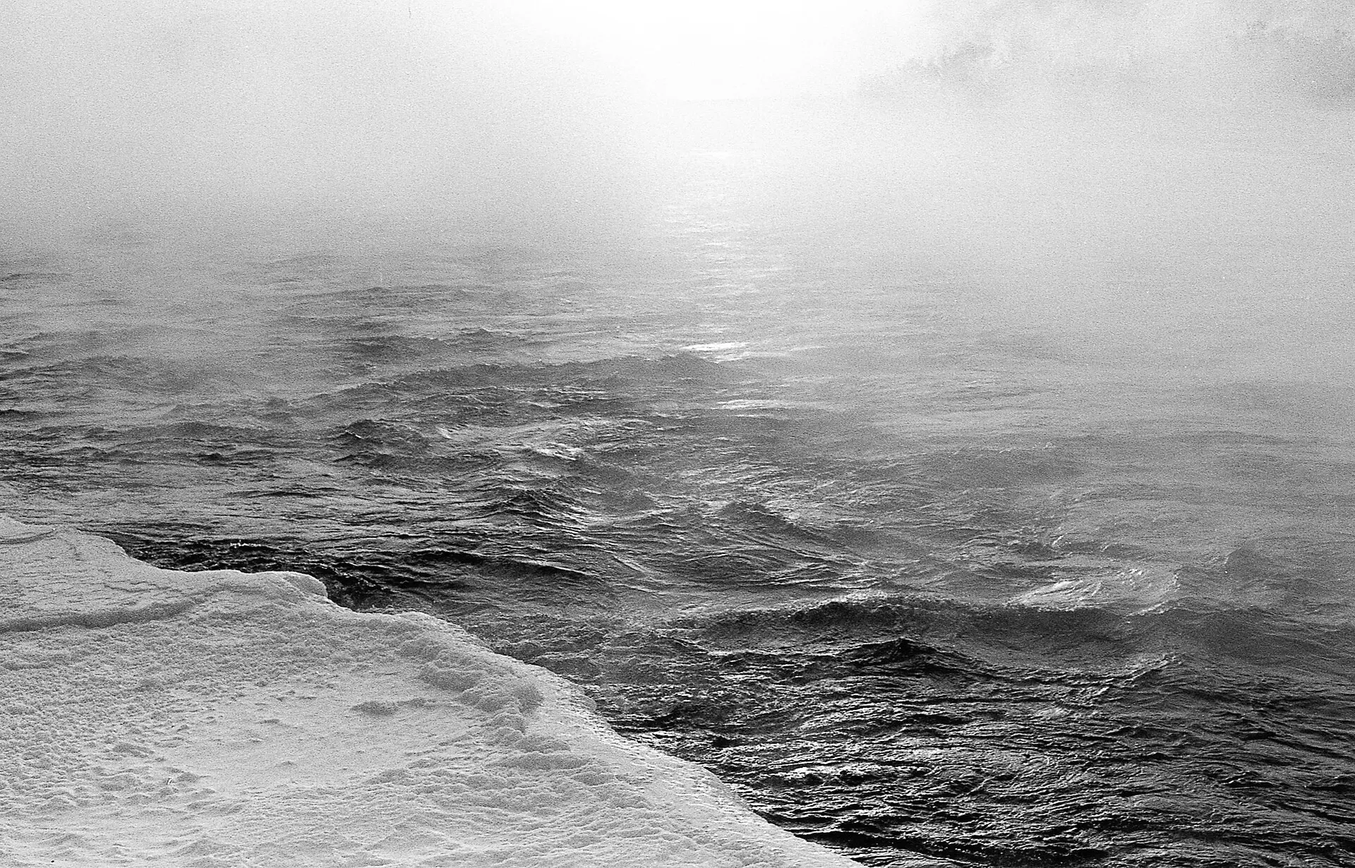 Ice fog rising off a dark river in black and white