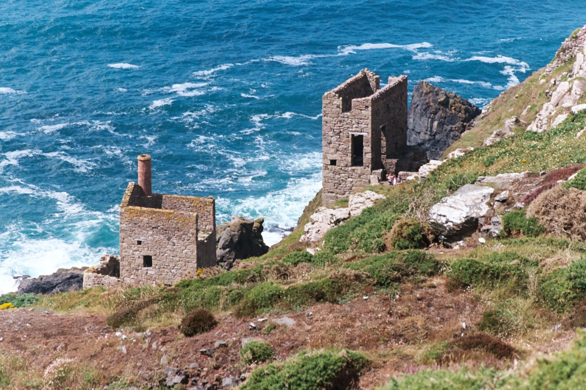Ruined engine houses of Botallack mine on a cliff above a blue sea