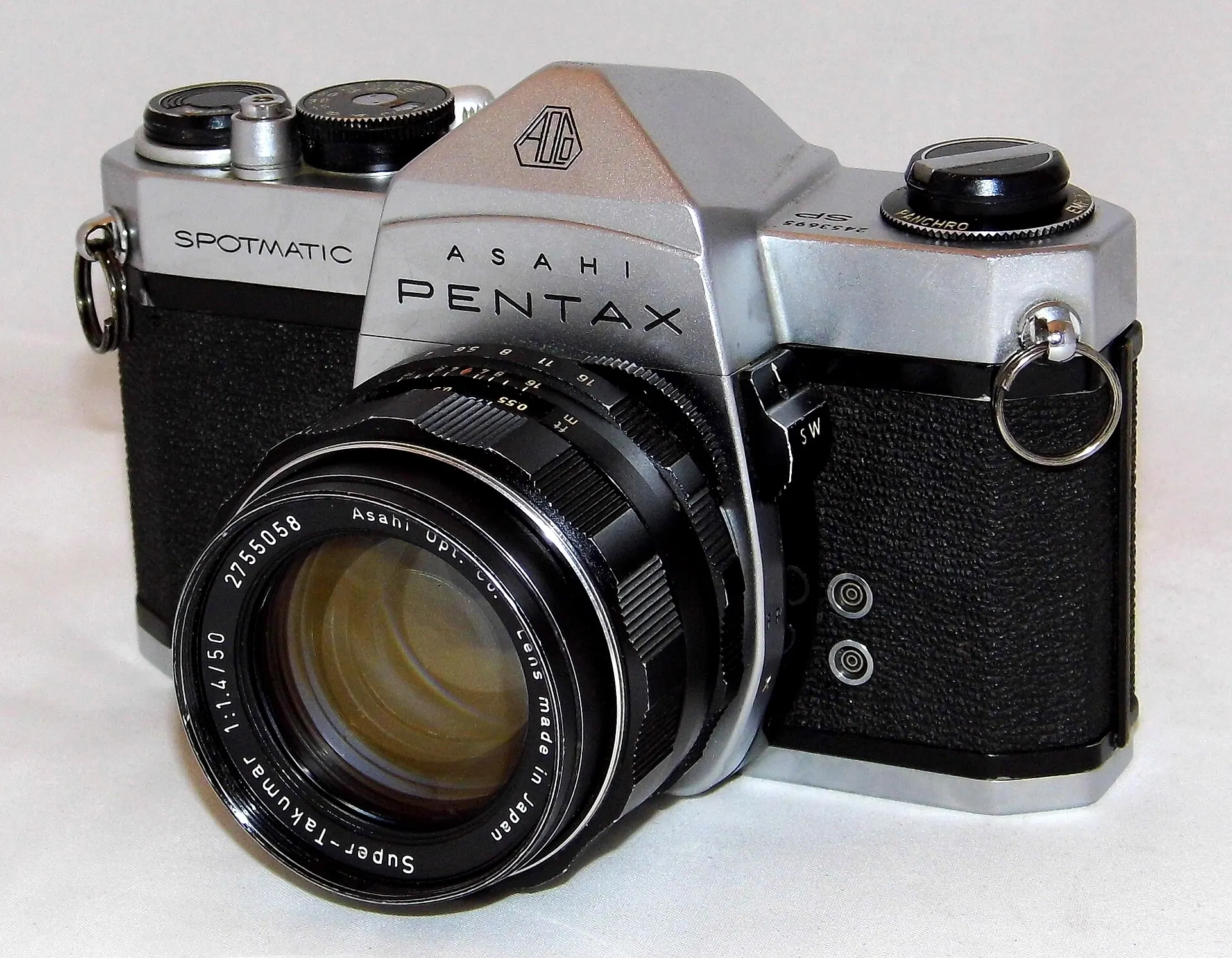Chrome Asahi Pentax Spotmatic with a Super-Takumar 50mm f/1.4 lens, seen from the front left on a plain background