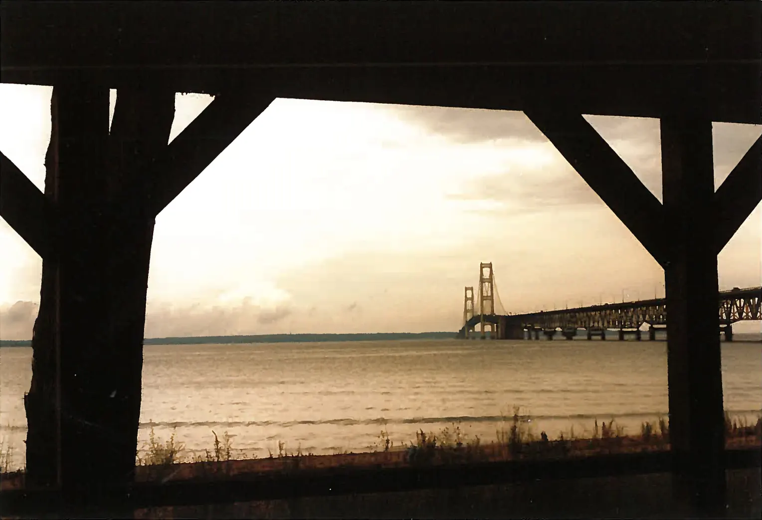 The Mackinac Bridge at dusk framed by dark wooden posts