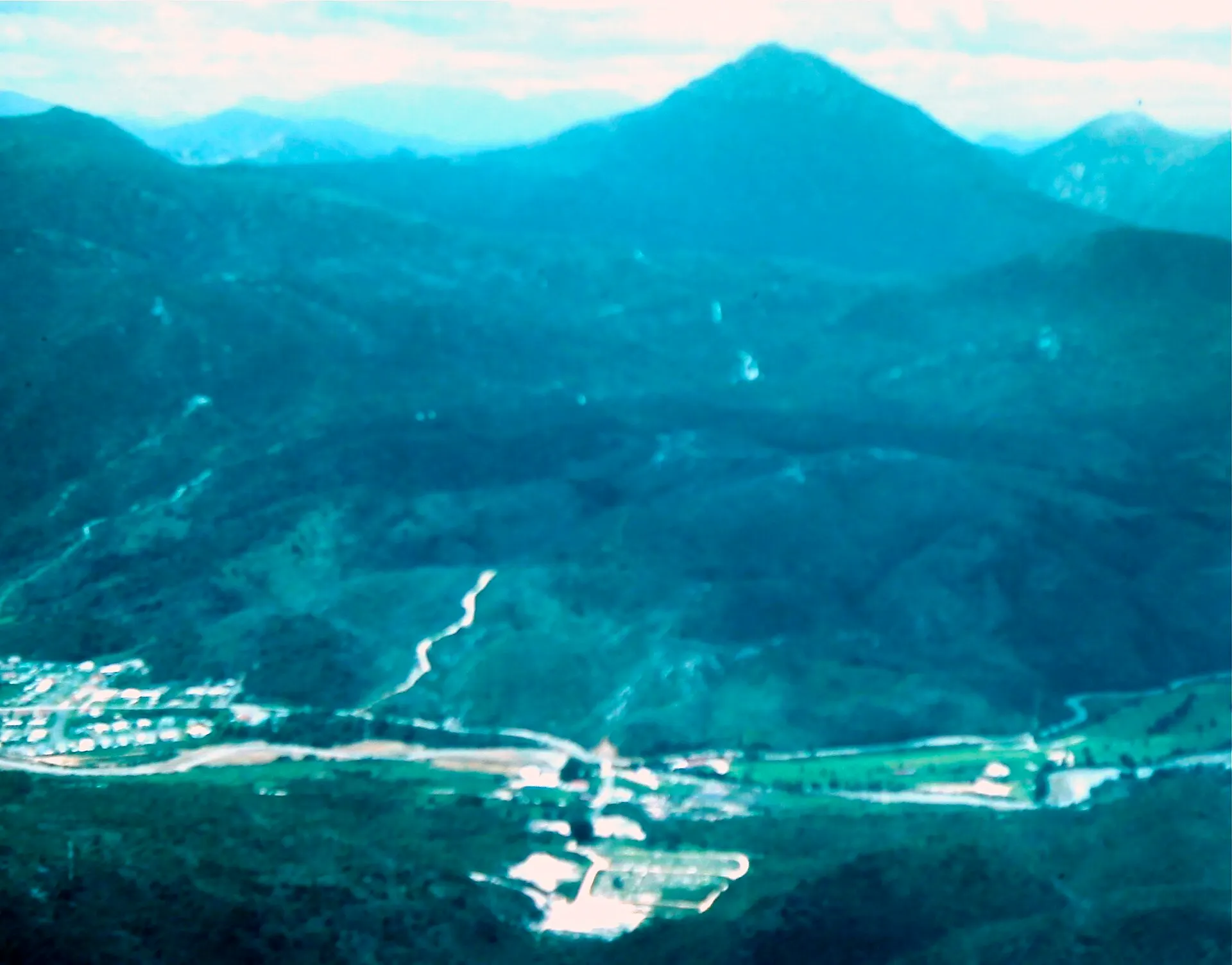 Aerial view of green mountains above a small town and airstrip