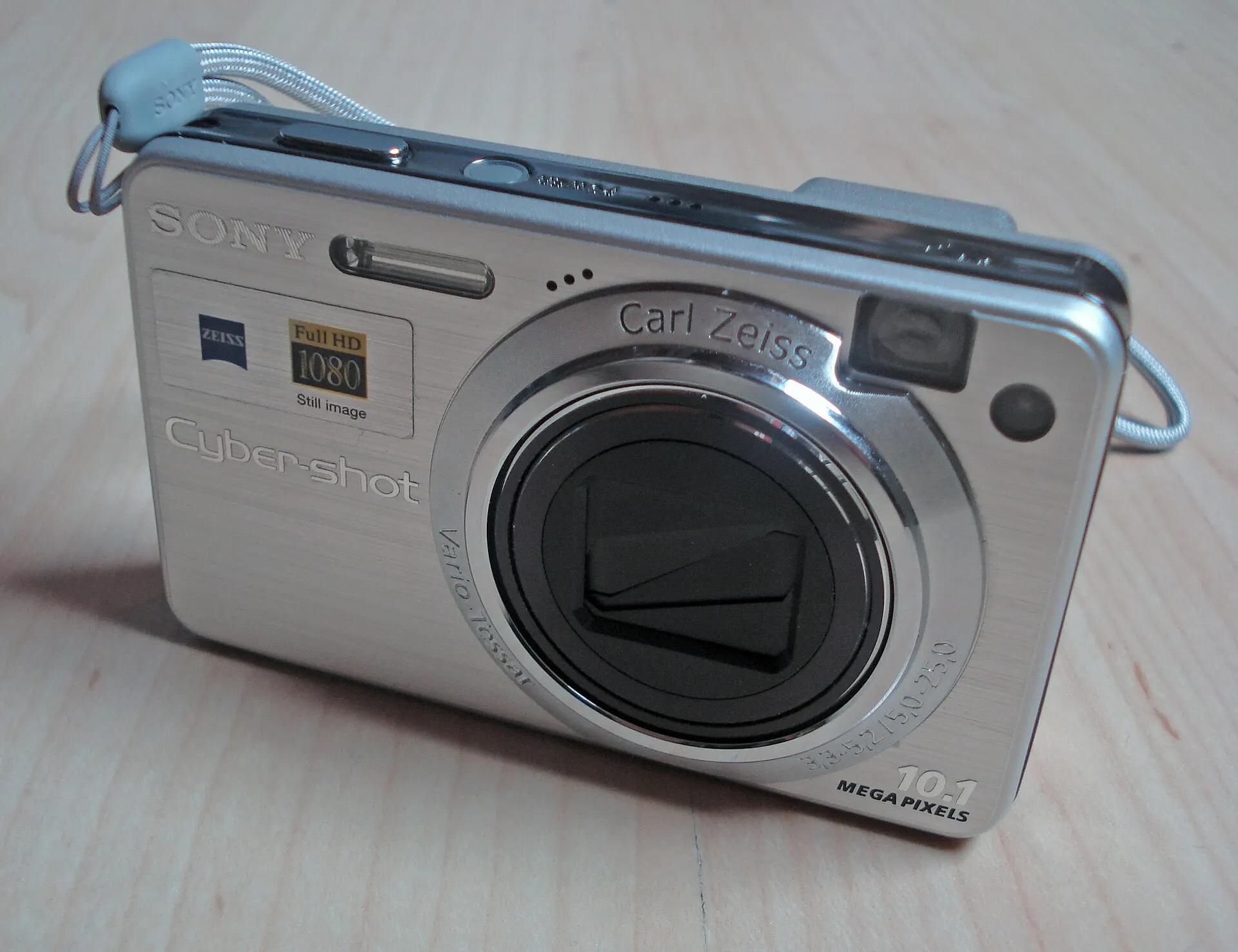 Silver Sony Cyber-shot DSC-W170 with a Carl Zeiss zoom lens and wrist strap on a wooden table