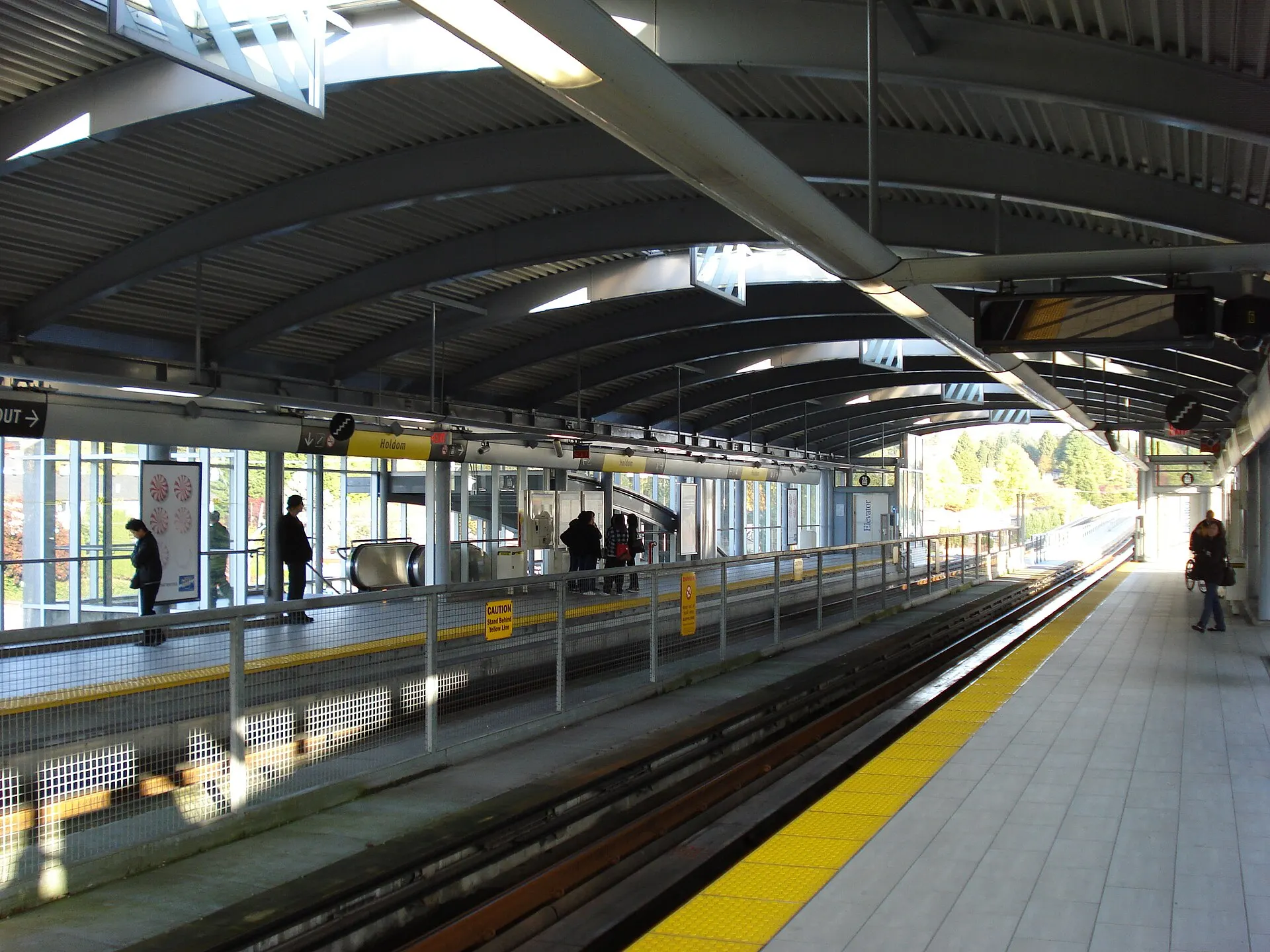 Covered elevated train platform with a few passengers waiting