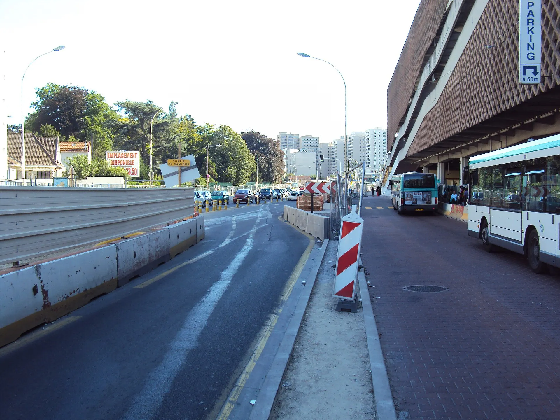 Street under construction with barriers and a city bus